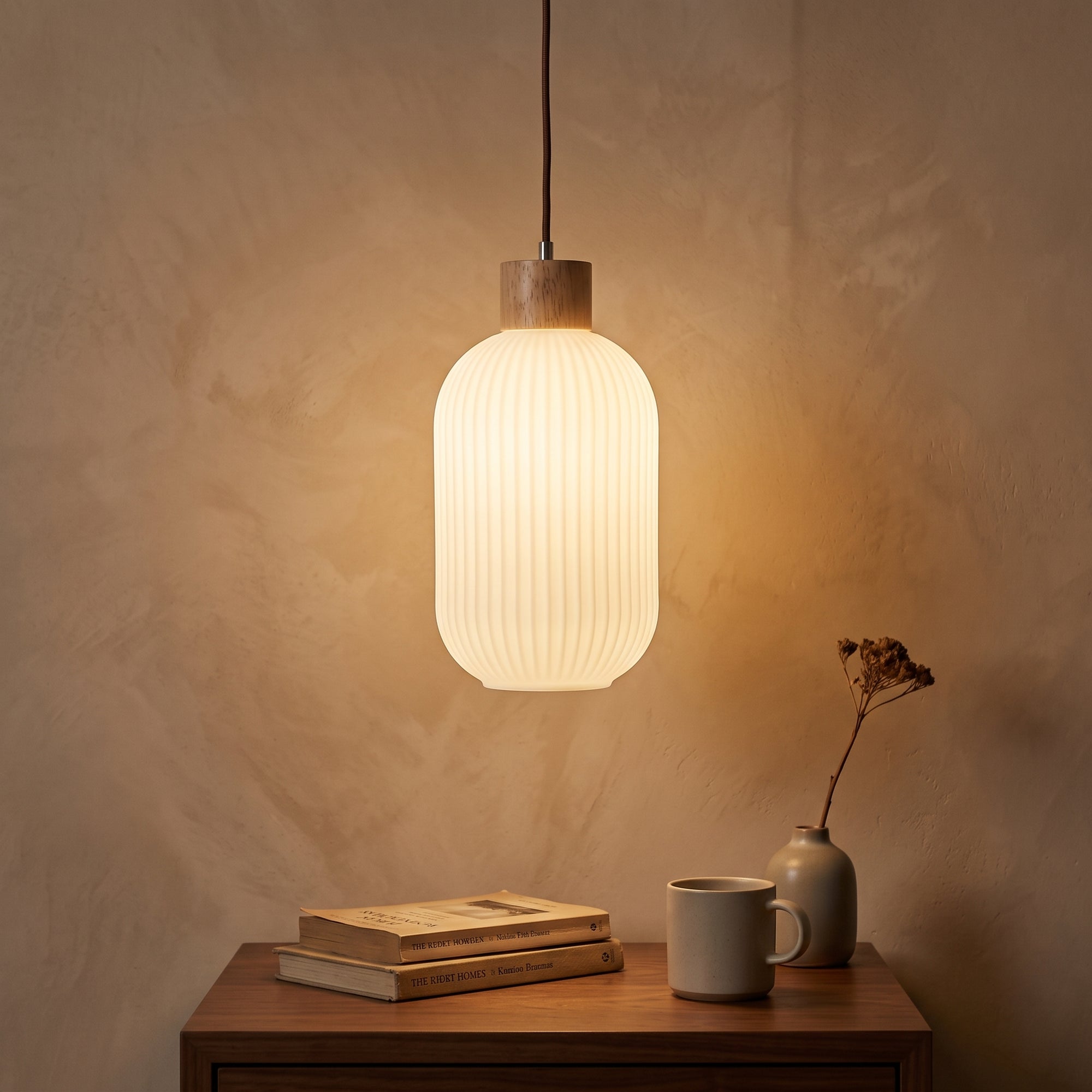 wold pendant light, Cylinder profile, hung low over a walnut bedside table at dusk